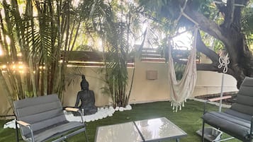 An outdoor seating area with two lounge chairs, a small table, and a hammock.