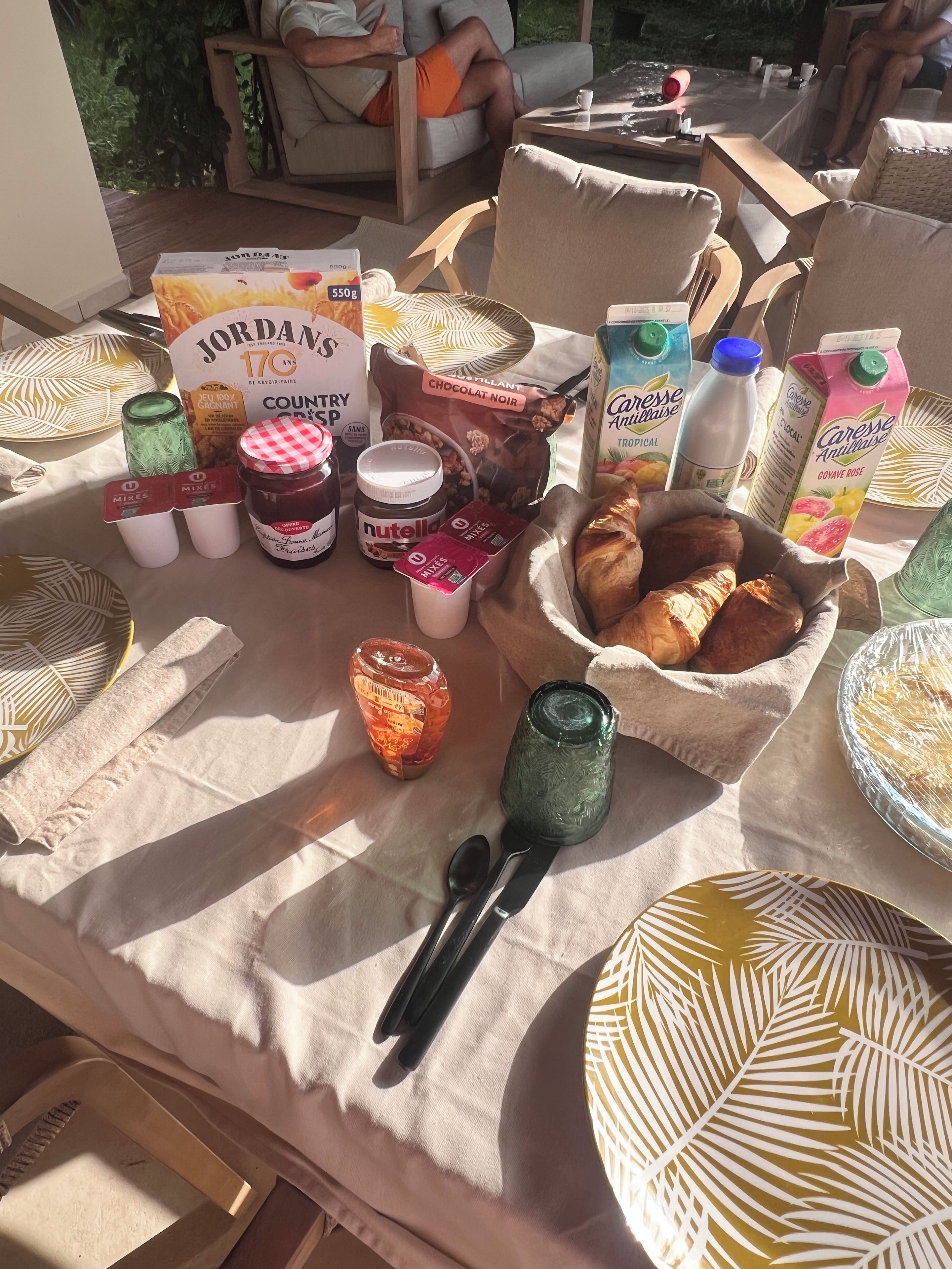 Aamiaispöytä, jossa on monenlaista syötävää ja lisukkeita, kuten leipää, leivonnaisia ja levitteitä.