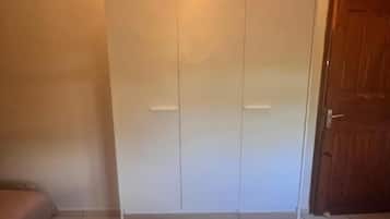 A room with a wardrobe, a patterned rug, and a door.