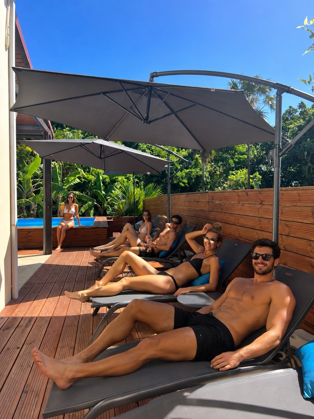 Un área junto a la piscina con sillones de descanso y una zona de estar techada.