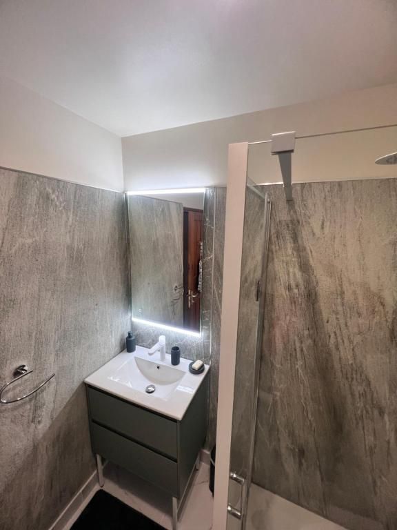 A bathroom with a white sink, mirror, and shower.