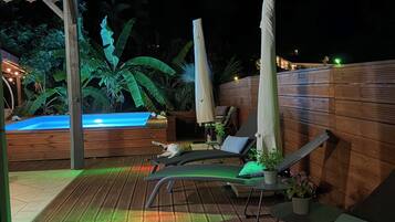 An outdoor deck with lounge chairs, a hot tub, and potted plants.