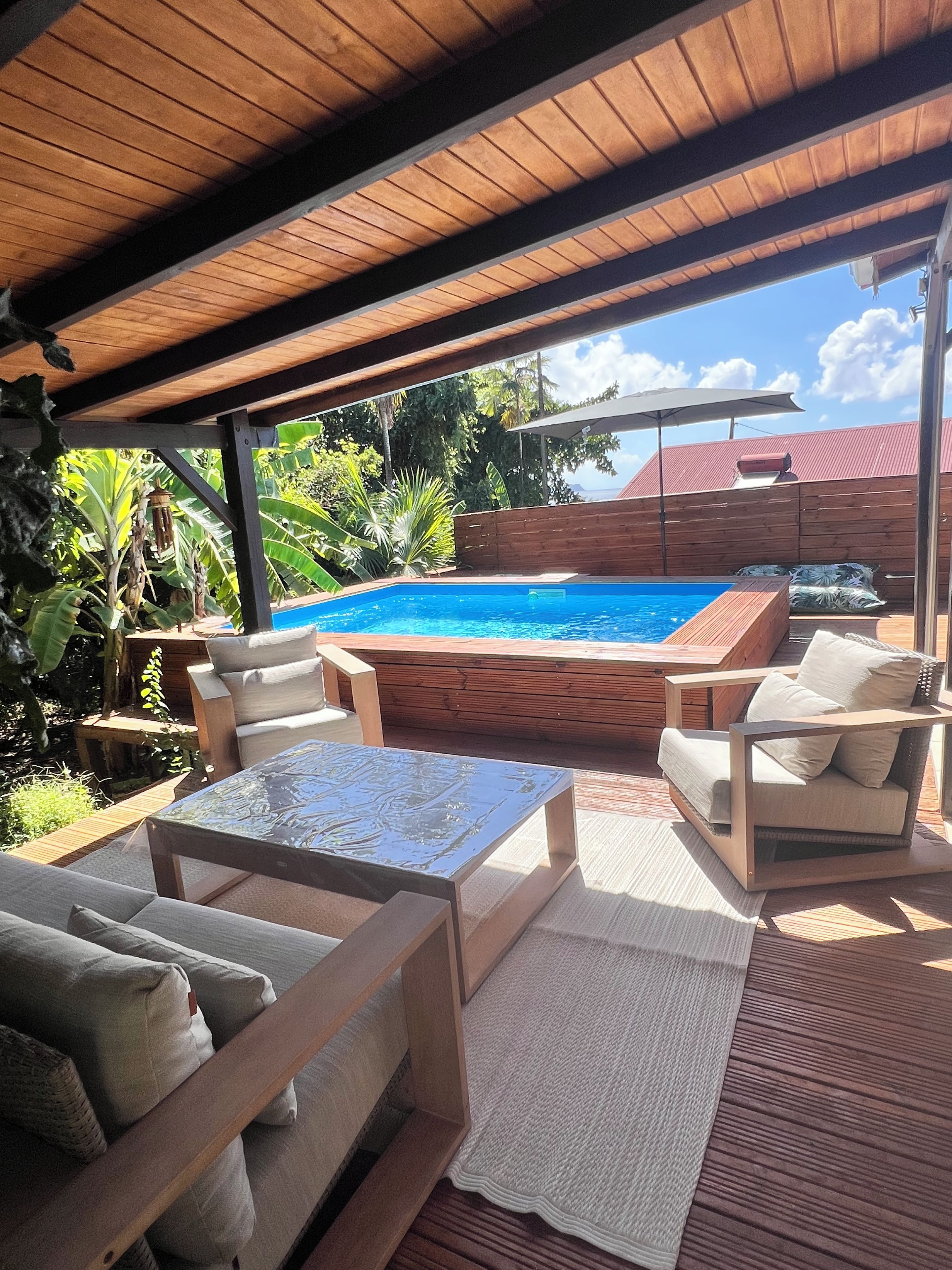 A covered outdoor area with a pool, lounge chairs, and a hot tub.