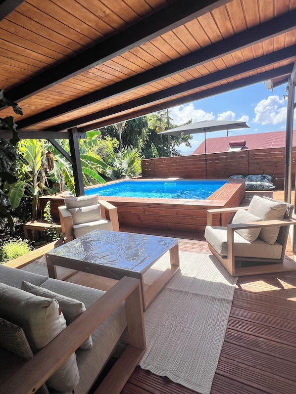 Un espacio al aire libre techado con piscina, sillas de descanso y jacuzzi.