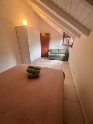 Un dormitorio con cama, armario y un sofá al fondo.