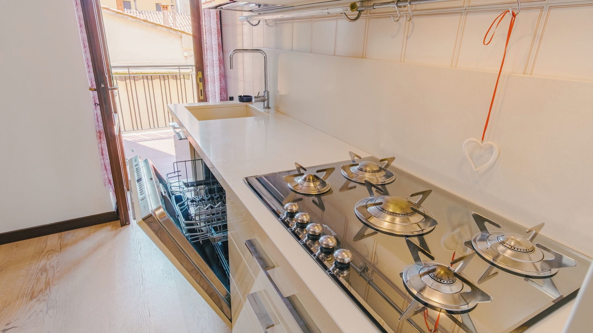 Una cocina equipada con estufa a gas, lavavajillas y lavabo.