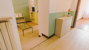 A room with a glass-top table, a white cabinet, and a shelf with various items. - Veronetta Living - Two Bedroom Apartment, Sleeps 5 (Verona)