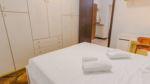 A hotel room with a bed, two towels, a desk, and a chair. - Veronetta Living - Two Bedroom Apartment, Sleeps 5 (Verona)
