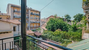 A residential area with multi-story buildings, balconies, and a garden area with trees and shrubs. - Veronetta Living - Two Bedroom Apartment, Sleeps 5 (Verona)