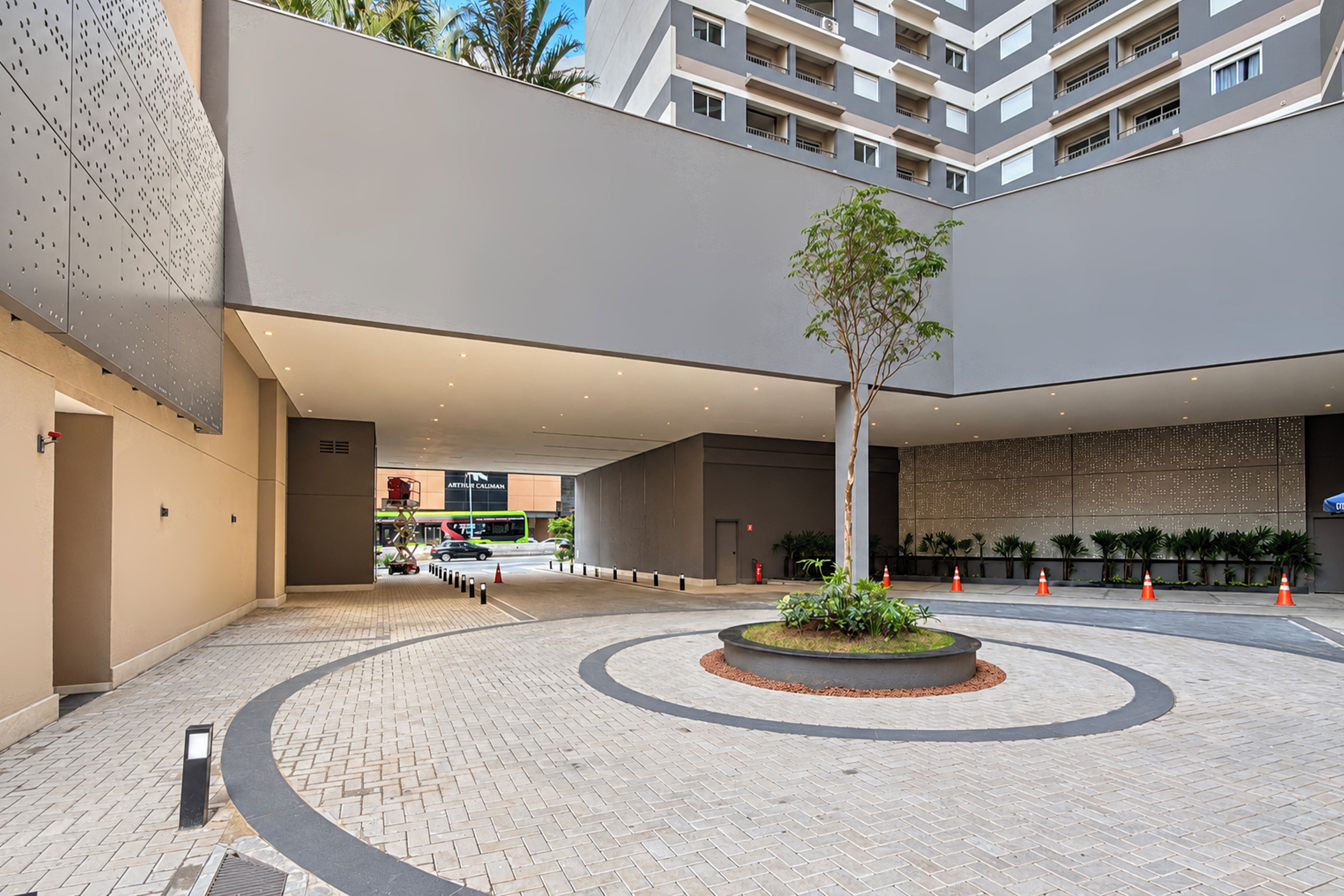 A spacious atrium with a central planter, a modern building facade, and a clear sky.