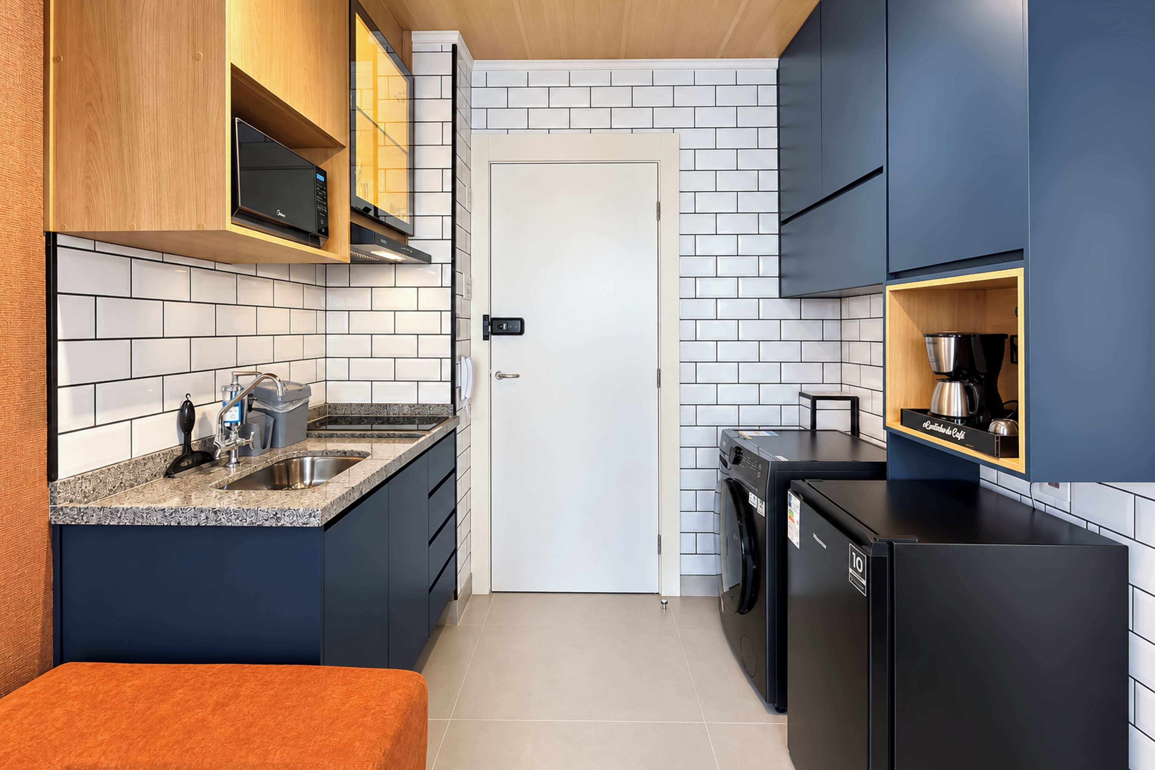 A compact kitchen with a built-in microwave, a sink, and a coffee machine.