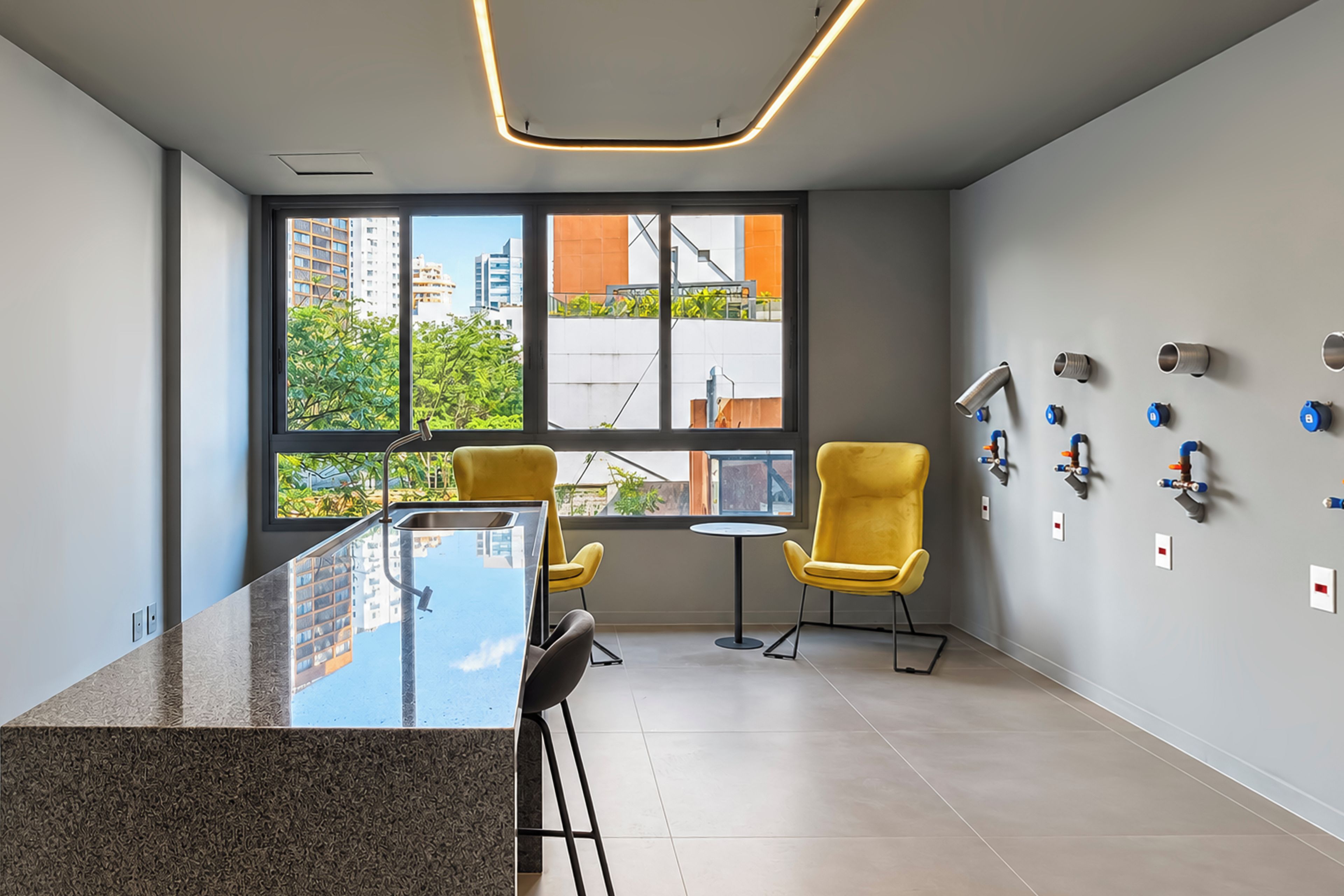 Une salle de réunion moderne, dotée d’une table en verre, de deux chaises jaunes, d’une petite table ronde et offrant une vue sur les bâtiments à travers de grandes fenêtres.