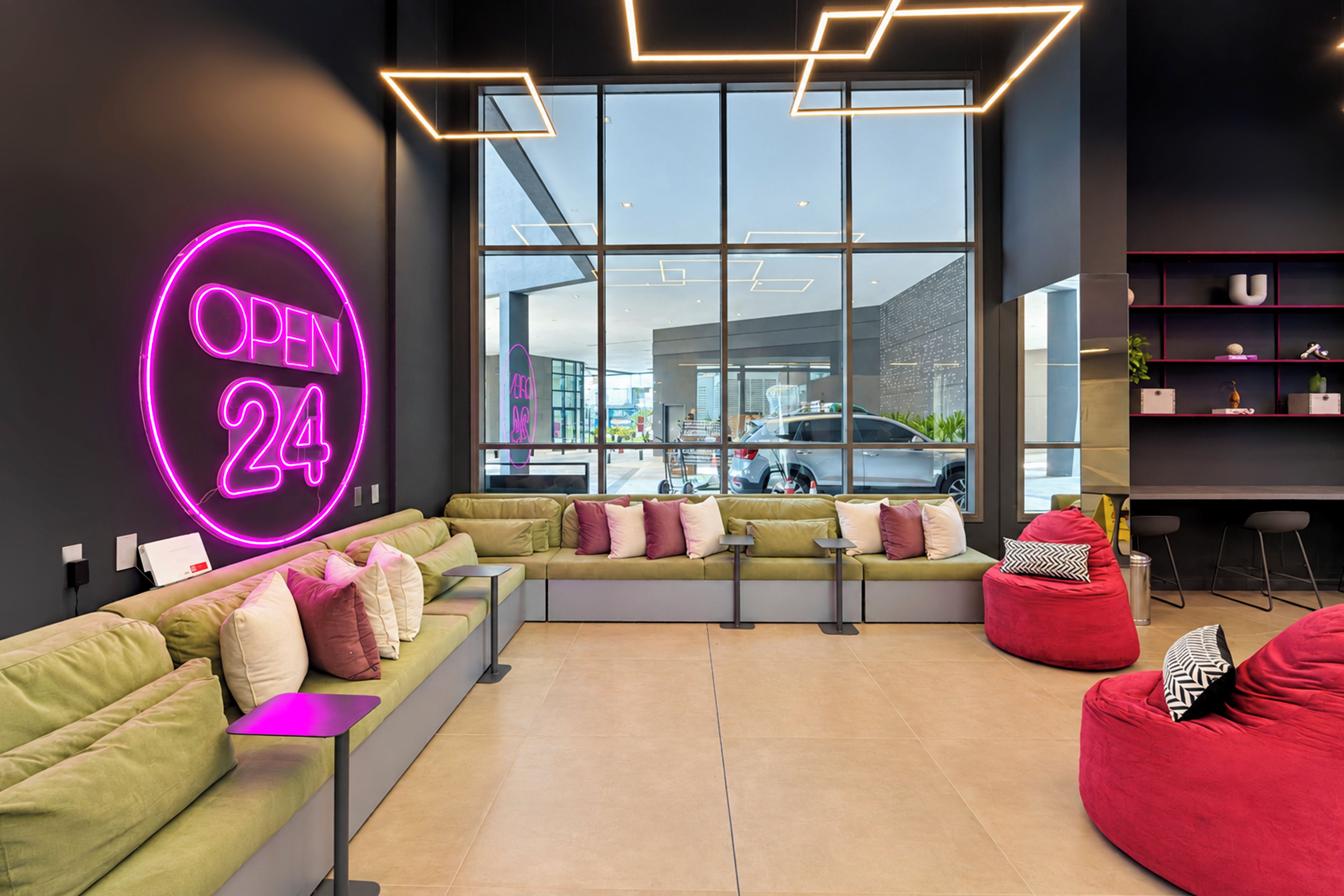 A modern lounge area with a neon sign, seating, and a view of the outside.