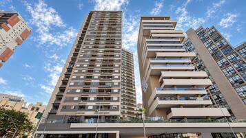 A modern high-rise building with multiple balconies and a clear sky.