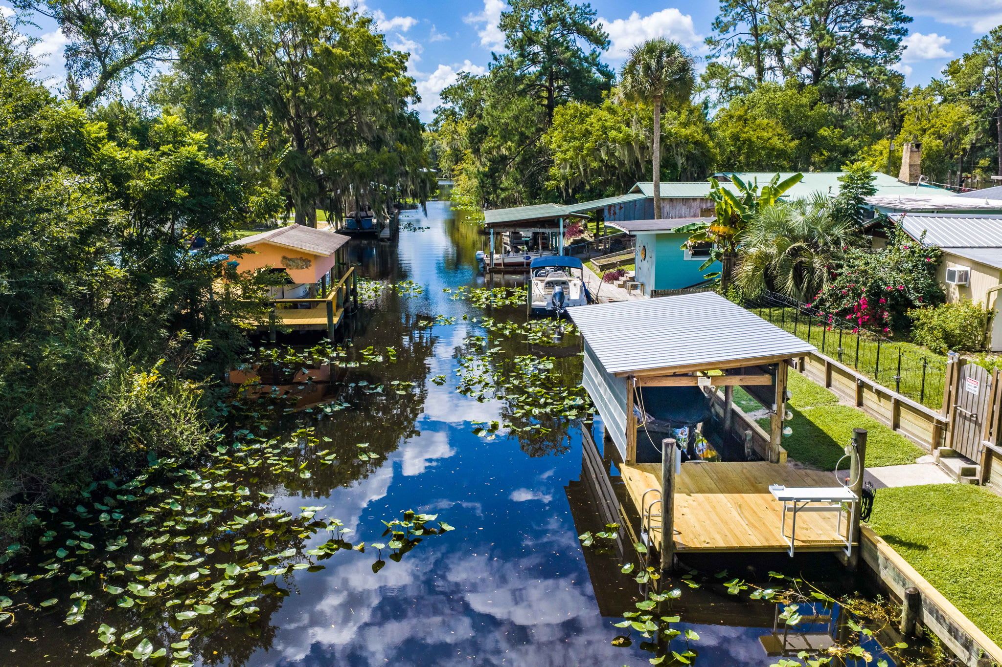 A riverside property with a dock, a small boat, and a house with a green roof.