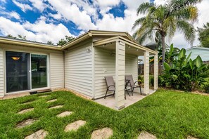 A house with a covered patio, a sliding glass door, and a well-maintained lawn. - Fisherman's Studio: Unit 1 (studio only) (Satsuma)