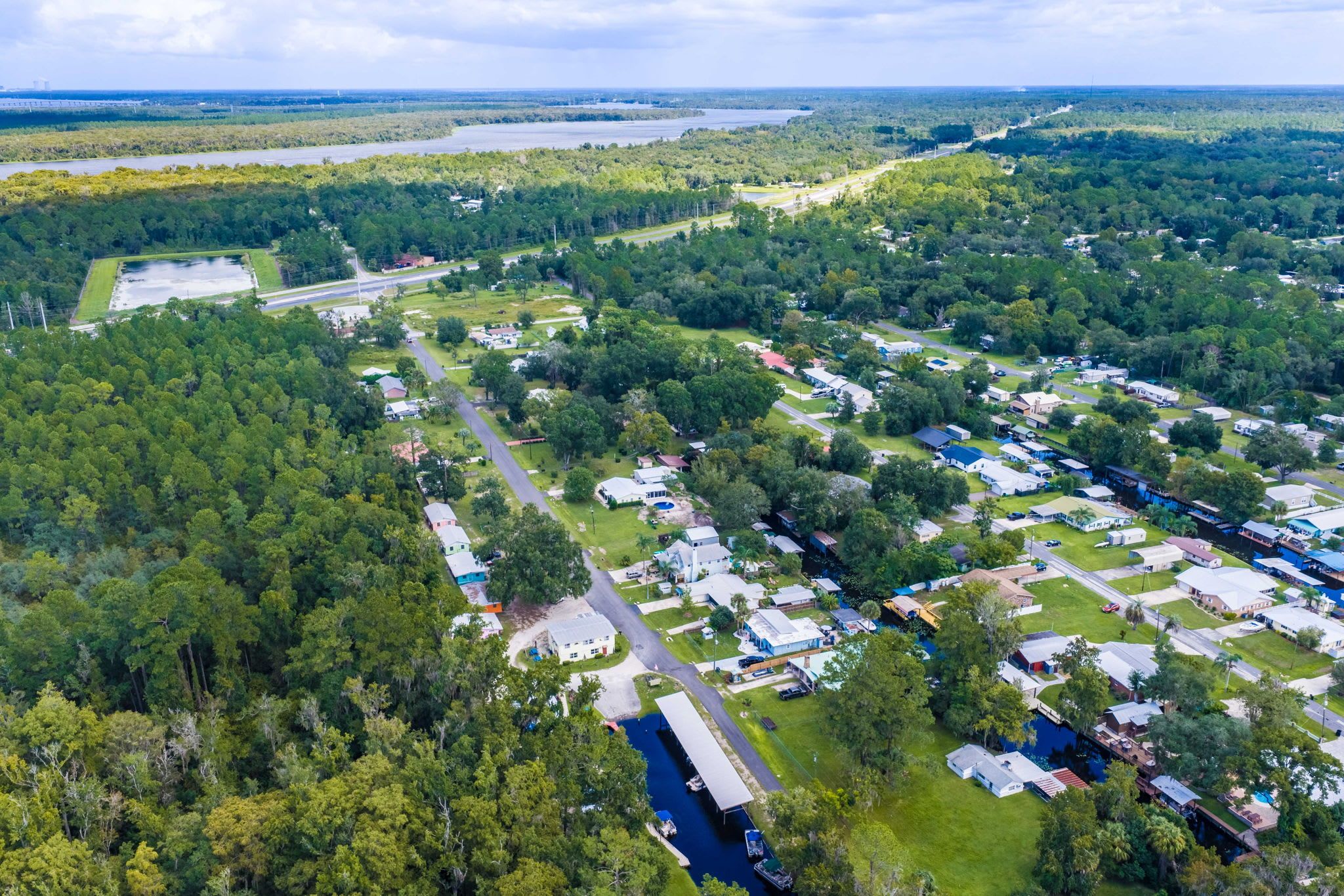 An aerial view of a campground with multiple RV sites, a main road, and a river.