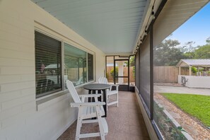 A covered patio with a table and chairs, a window with blinds, and a view of a backyard. - Fishermans Retreat - Unit 1 + 2 (entire property) (Satsuma)
