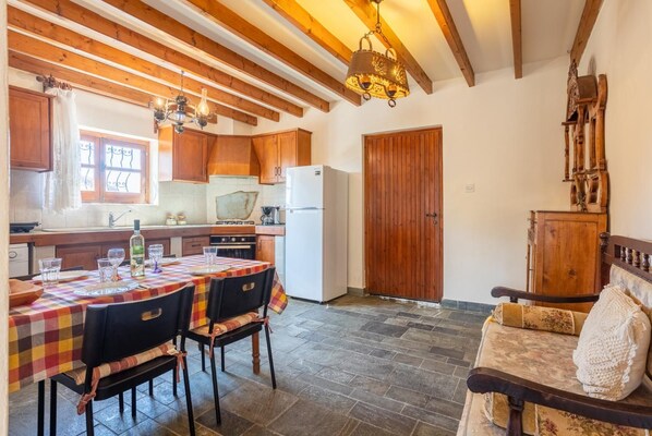 Eine Küche mit Holzausstattung, einem Esstisch mit Stühlen, einem Kühlschrank und einer Holztür.