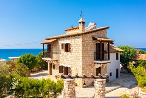 A stone house with a balcony, a chimney, and a view of the sea. - Villa Petroktisto - Three Bedroom Villa, Sleeps 6 (Pomos)