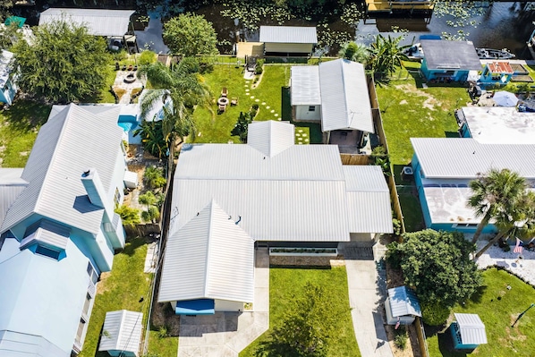 A residential area with multiple houses, a central building with a unique roof design, and a small pond with lily pads. - Fisherman's Reel Retreat: Unit 2 (Main home only) (Satsuma)
