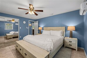 A bedroom with a bed, bedside tables, a ceiling fan, and a mirror. - Fisherman's Reel Retreat: Unit 2 (Main home only) (Satsuma)