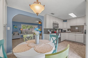 A dining area with a round table, chairs, and a vase with flowers. - Fisherman's Reel Retreat: Unit 2 (Main home only) (Satsuma)
