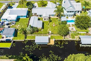 A residential area with multiple houses, a swimming pool, and a dock over water. - Fisherman's Reel Retreat: Unit 2 (Main home only) (Satsuma)