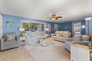 A living room with a sofa, a coffee table, and a ceiling fan. - Fisherman's Reel Retreat: Unit 2 (Main home only) (Satsuma)