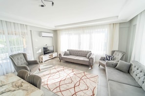 A modern living room with a grey sofa set, a coffee table, and a TV on a white cabinet. - Villa Dogakent 4 - Four Bedroom Villa, Sleeps 8 (Okçular)