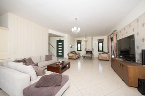 A spacious living area with a sofa set, a coffee table, a fireplace, and a television. - Villa Diamantis - Six Bedroom Villa, Sleeps 12 (Rethymno)