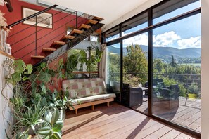 A modern interior with a wooden staircase, a bench, and a large glass door leading to a balcony with a view of mountains. - Villa 'Terre de Lumières' with View of Mount Néron in a Natural Setting (Quaix-en-Chartreuse)