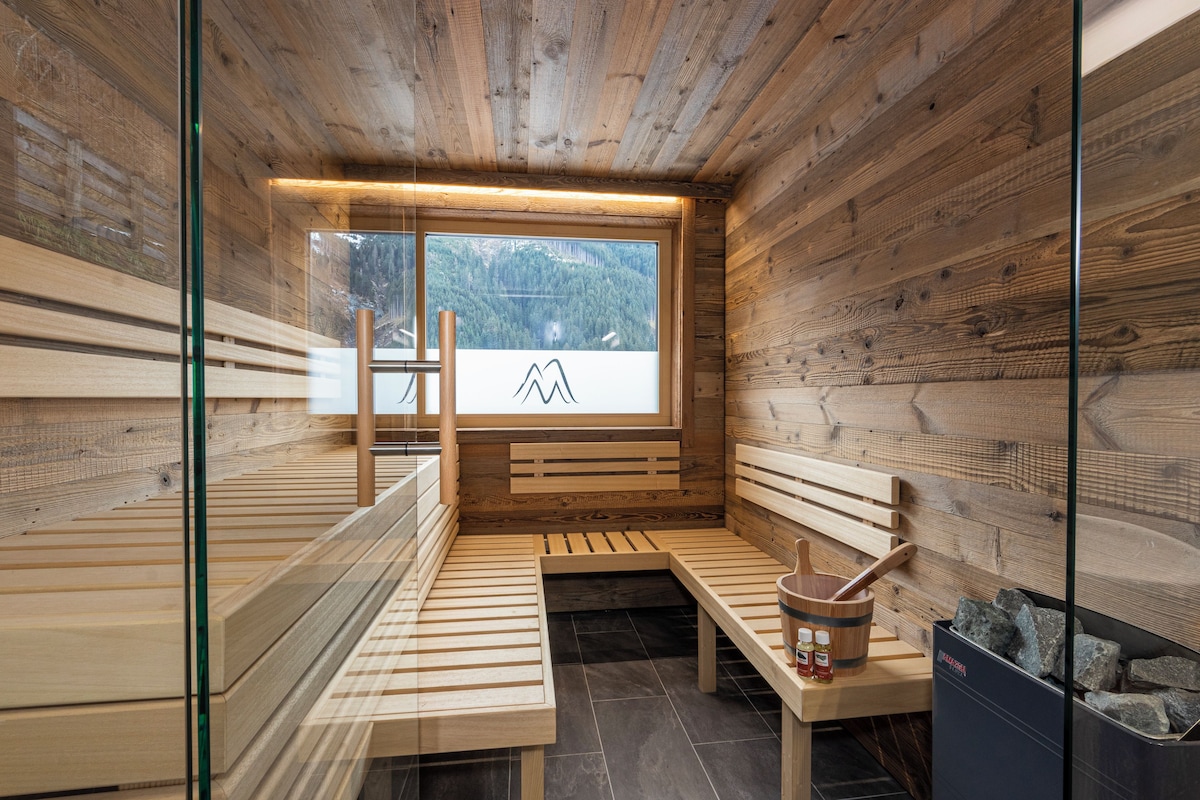 A sauna with wooden benches, a wooden bucket, and a stone-filled container.