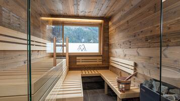 A sauna with wooden benches, a wooden bucket, and a stone-filled container.