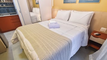 Ein Hotelzimmer mit Bett, Nachttisch, Kleiderschrank und Spiegel.