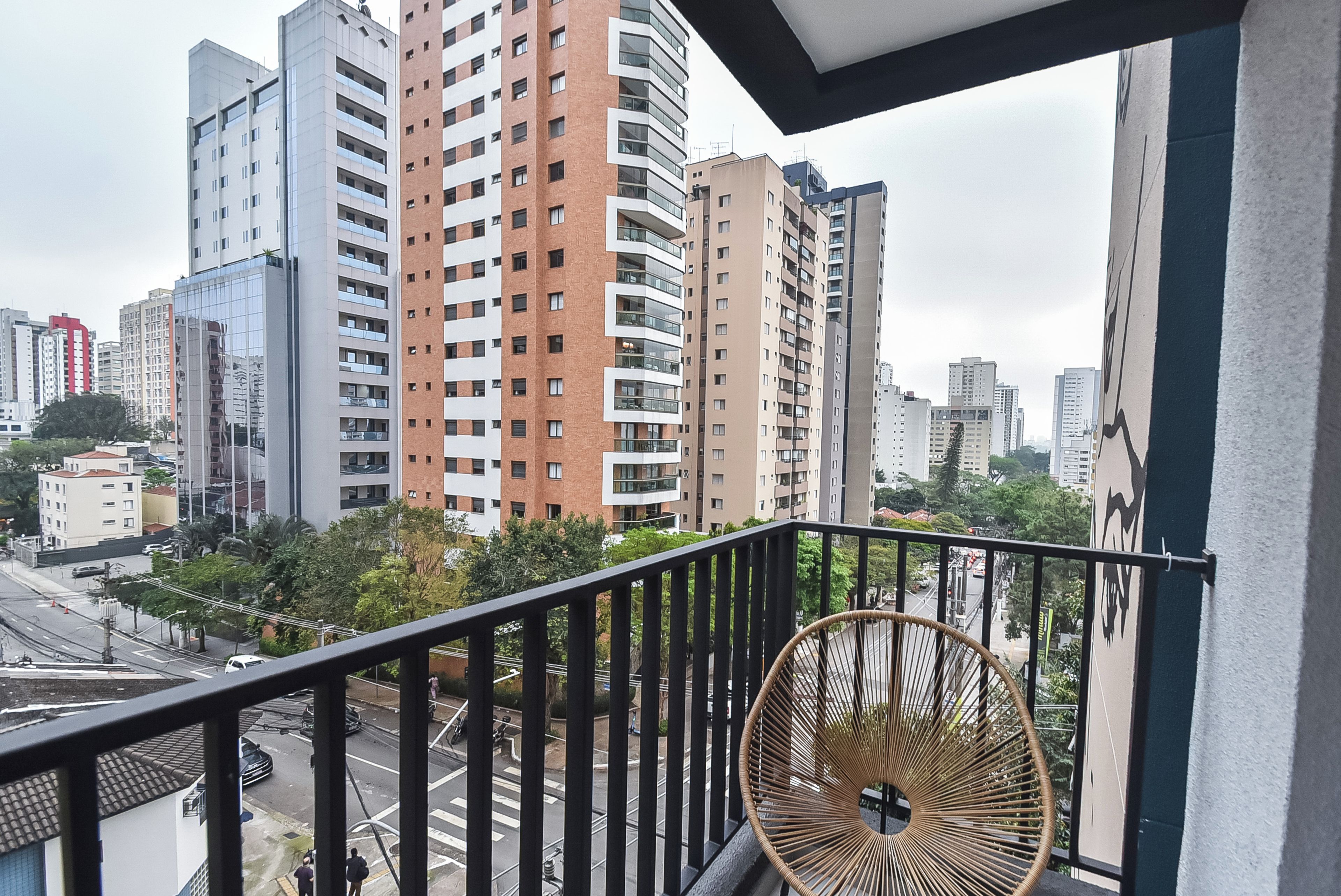 A balcony with a view of a cityscape, featuring modern buildings and a street below.