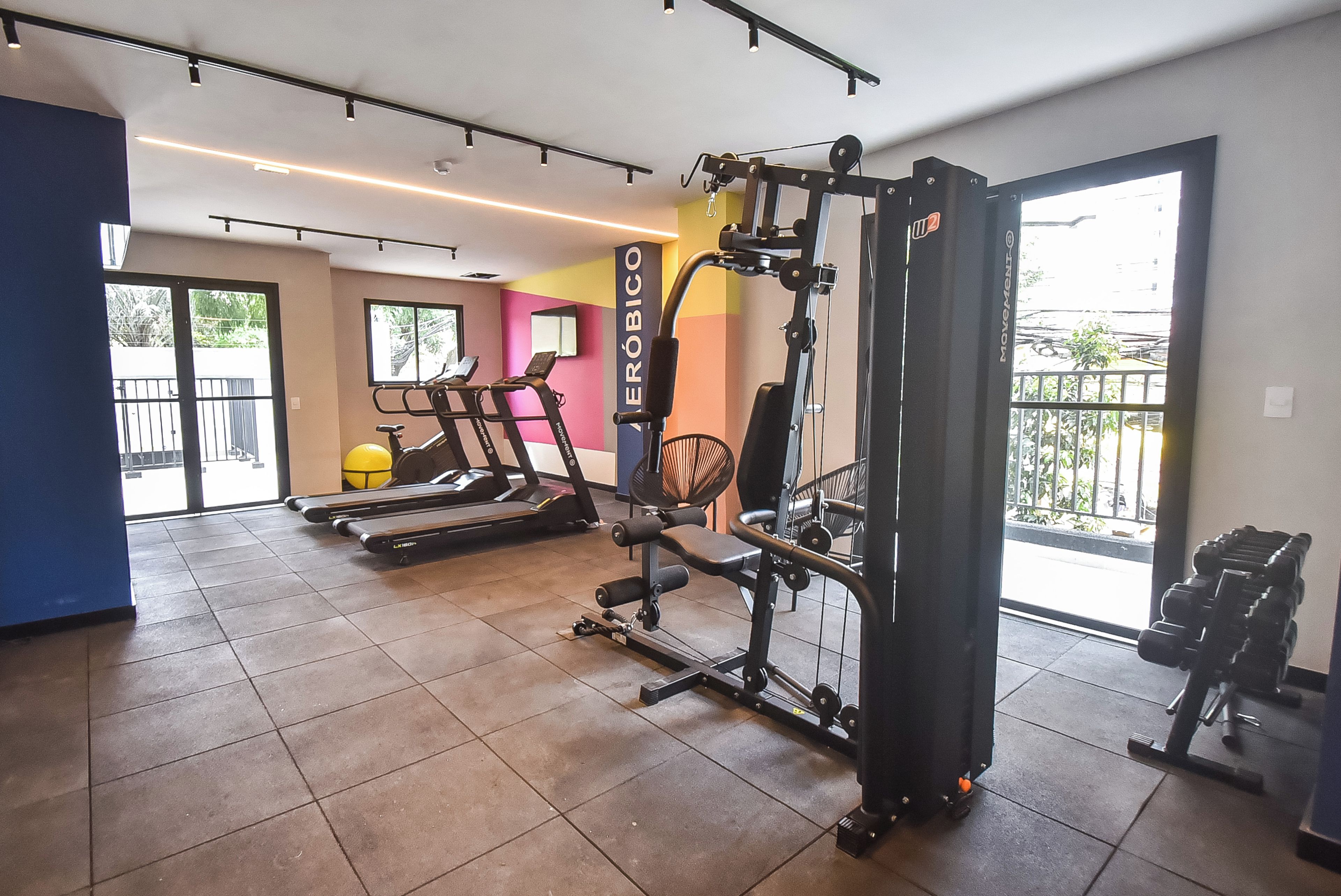 A gym with cardio equipment, weight machines, and a view of the outside.