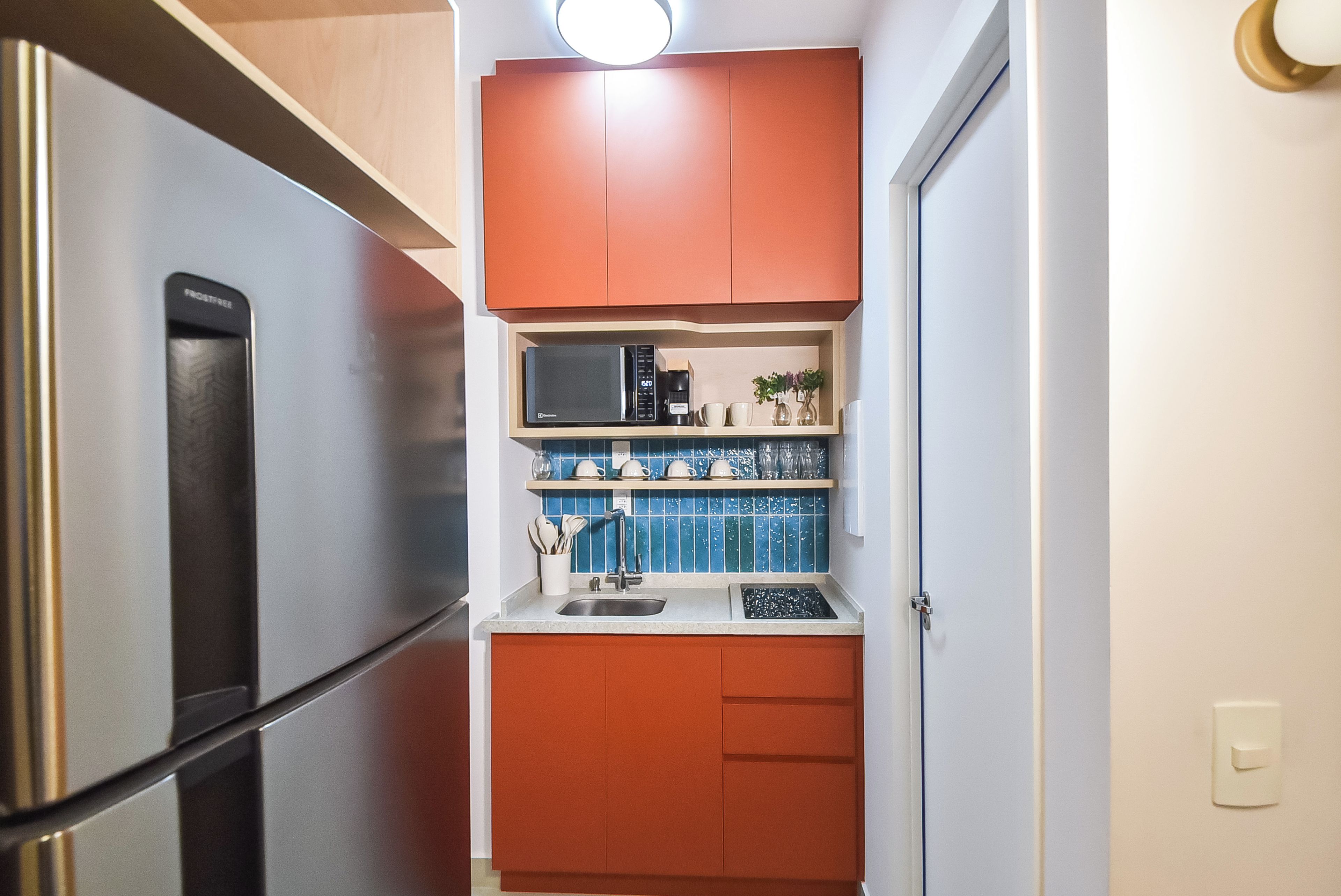 A compact kitchen with a stainless steel refrigerator, a microwave, and a sink.