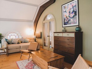 A cozy living room with a sofa, a wooden coffee table, and a cabinet. - Chapel of Arts (Criccieth)