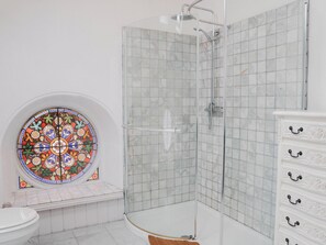 A bathroom with a shower, a toilet, and a decorative stained glass window. - Chapel of Arts (Criccieth)