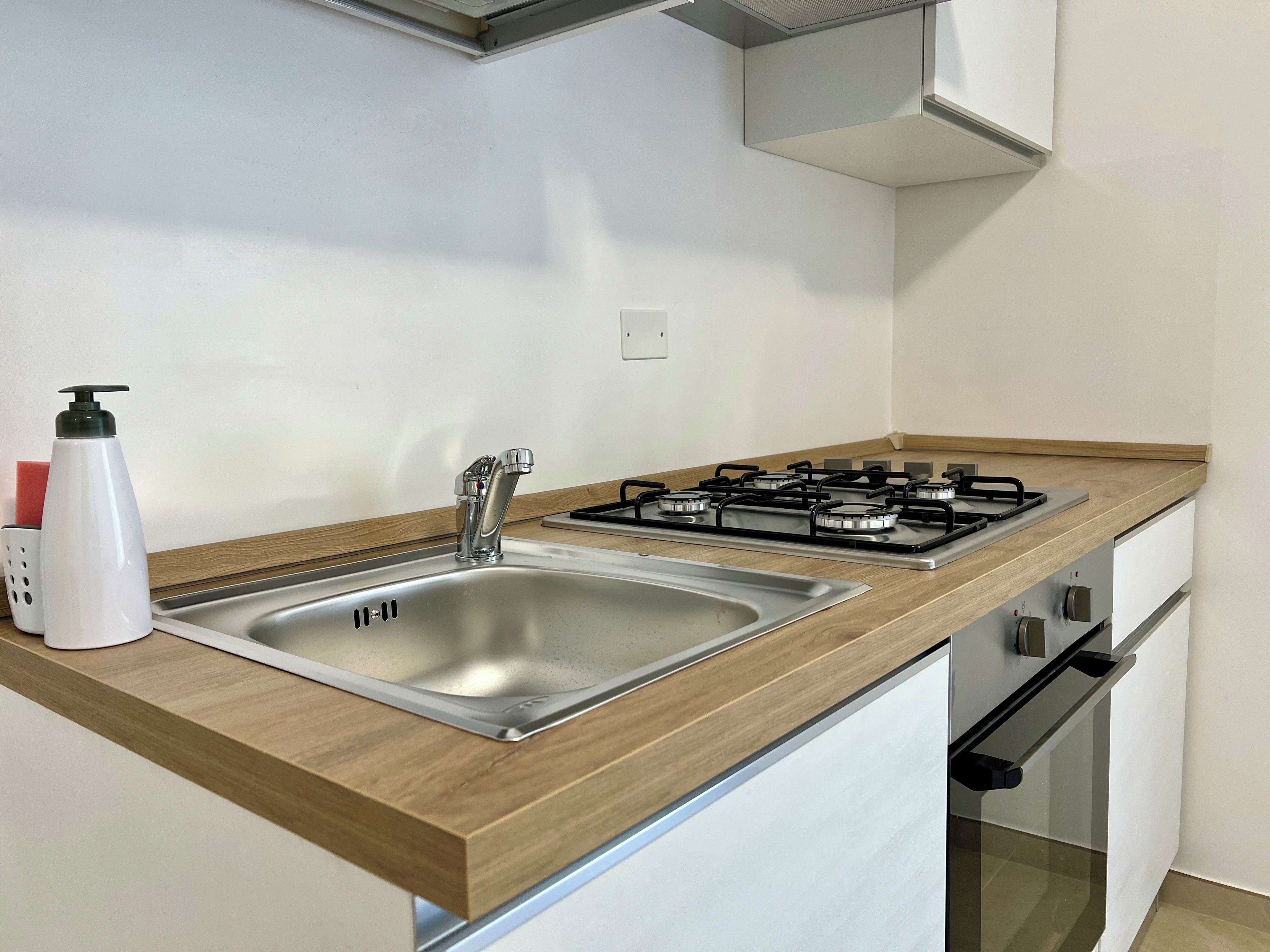 A modern kitchen with a stainless steel sink, a gas stove, and wooden countertops.