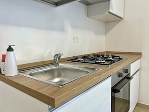 A modern kitchen with a stainless steel sink, a gas stove, and wooden countertops. - Villa Favorita: Casa Beige—Between Nature and Mondello (Palermo)