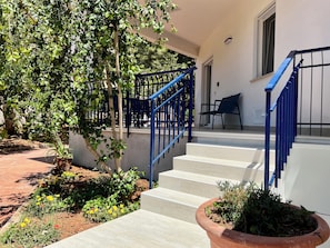 Un escalier avec des rampes bleues menant à un palier où se trouve une chaise.