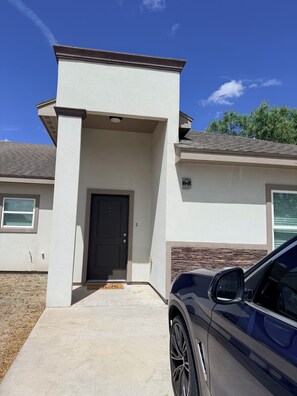 A modern two-story house with a black front door, a driveway, and a parked car. - Perfect Getaway Duplex for Short or Long Term Stays! (Brownsville)