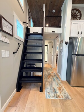 A staircase leading to a second floor, a kitchen with a stainless steel refrigerator, and a rustic wooden ceiling. - Cozy Creekside Retreat  Private Hot Tub Near Pigeon Forge (Seymour)