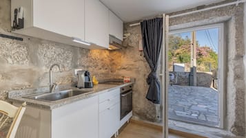 A compact kitchen with a stone wall, a sink, a coffee maker, and a view of the outside.