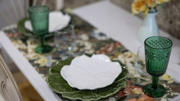 Una mesa dispuesta con cristalería verde y platos blancos sobre un mantel con estampado floral.