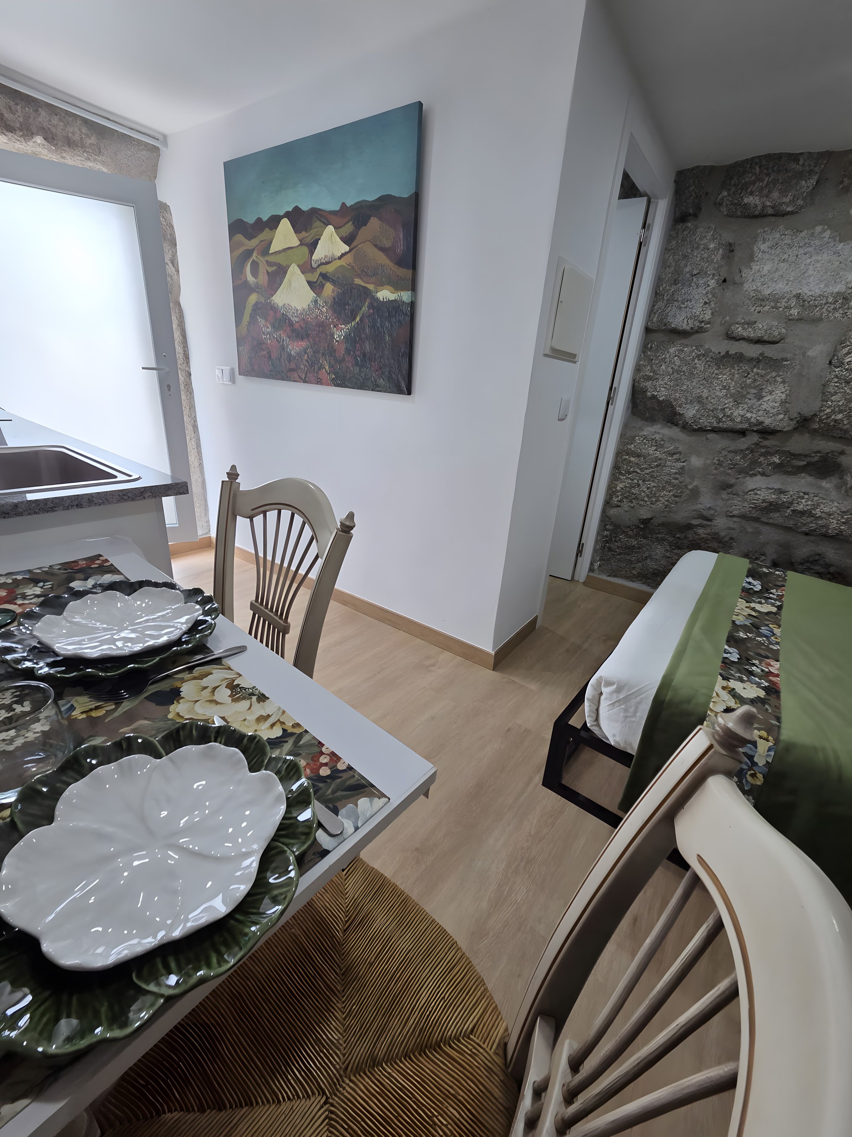 Ein Essbereich mit einem Tisch für vier Personen, einem Gemälde an der Wand und einer Steinwand im Hintergrund.