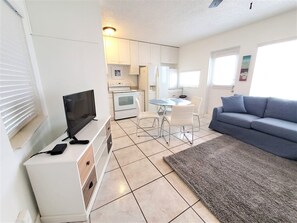 A compact living space with a kitchenette, a flat-screen TV, a sofa, and a dining area. - Comfy 1 Bed 1 Bath Apt Minutes to the Beach, Pool (Lauderdale-by-the-Sea)
