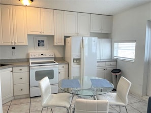 A kitchen with white cabinets, a glass table, and two chairs. - Comfy 1 Bed 1 Bath Apt Minutes to the Beach, Pool (Lauderdale-by-the-Sea)